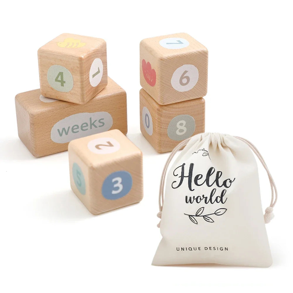 Wooden baby milestone blocks with numbers and weeks engraving alongside a "Hello world" drawstring pouch