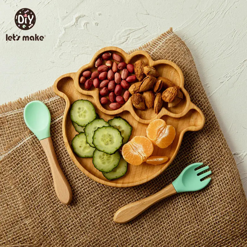 Safe baby dinnerware set with wooden divided plate shaped like a sheep and silicone baby spoon and fork on burlap background