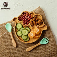 Safe baby dinnerware set with wooden divided plate shaped like a sheep and silicone baby spoon and fork on burlap background