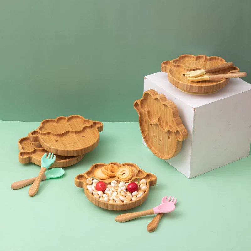 Cartoon bamboo baby feeding set with non-slip plate, spoon, and fork for self-feeding.