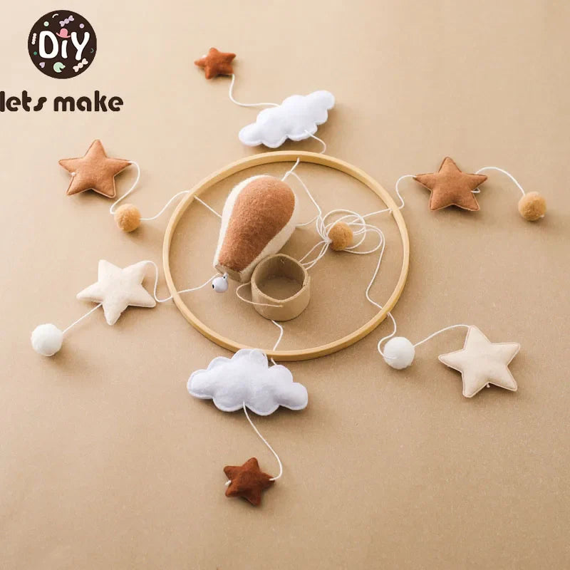 Wooden hot air balloon baby mobile with musical features, stuffed clouds and stars hanging from a circular frame, unisex infant crib toy.
