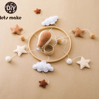 Wooden hot air balloon baby mobile with musical features, stuffed clouds and stars hanging from a circular frame, unisex infant crib toy.