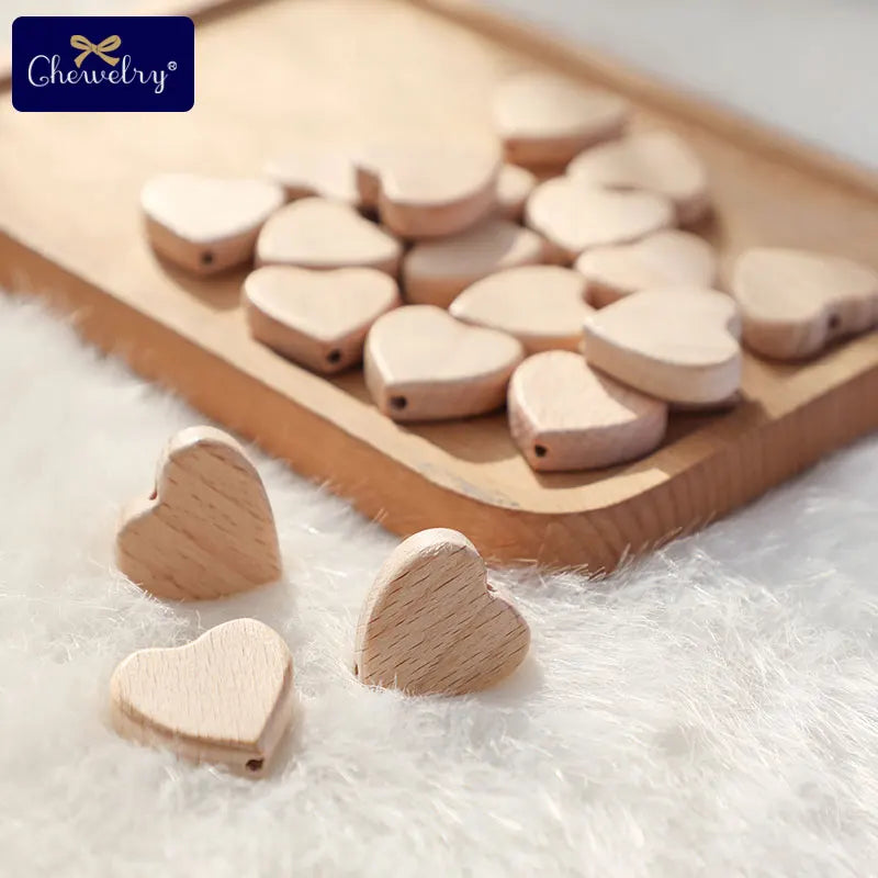 Beech wooden heart-shaped baby teether beads set on a wooden tray and soft surface, natural and safe for DIY pacifier clips and toys.