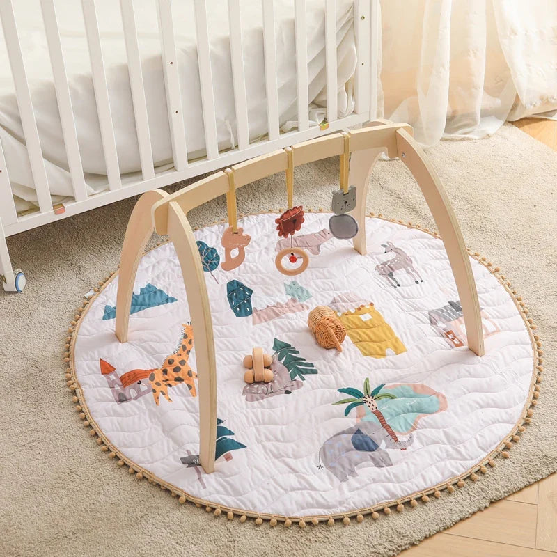 Montessori wooden baby play gym with foldable geometric frame and hanging sensory rattles on a round animal-themed mat
