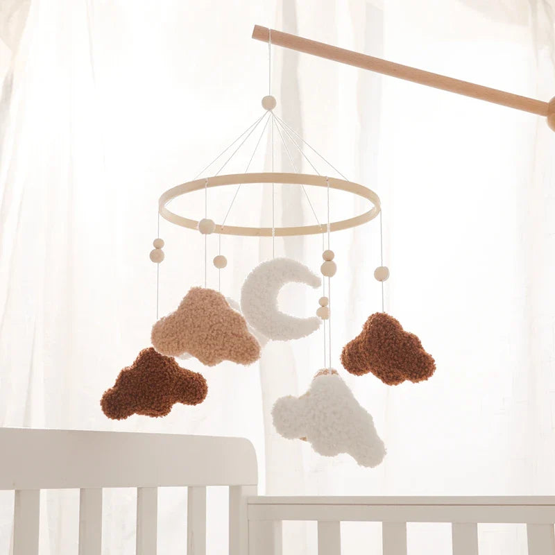 Wooden crib mobile with hanging crochet clouds and lamb in soft neutral tones for baby nursery.