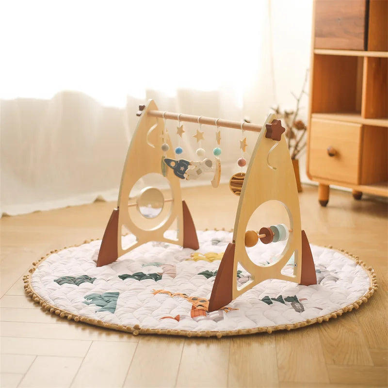 Natural wooden baby play gym with animal-themed hanging toys and soft rattle elements on round quilted mat