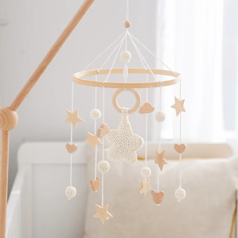 Wooden baby crib mobile with crochet stars, wooden beads, and gentle rattle in neutral colors for sensory development and soothing.